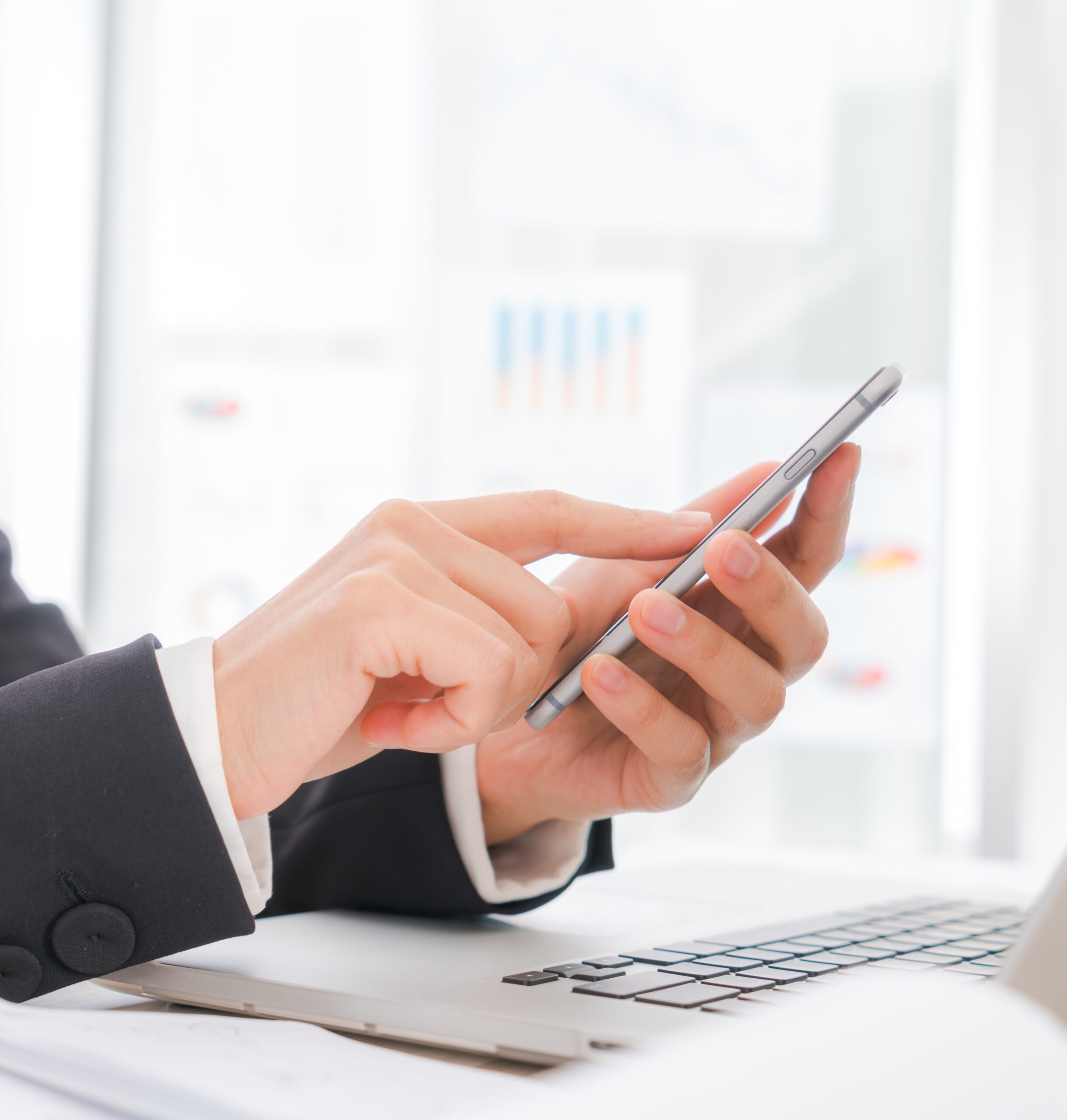 closeup of business woman hand typing on laptop keyboard with mobile phone